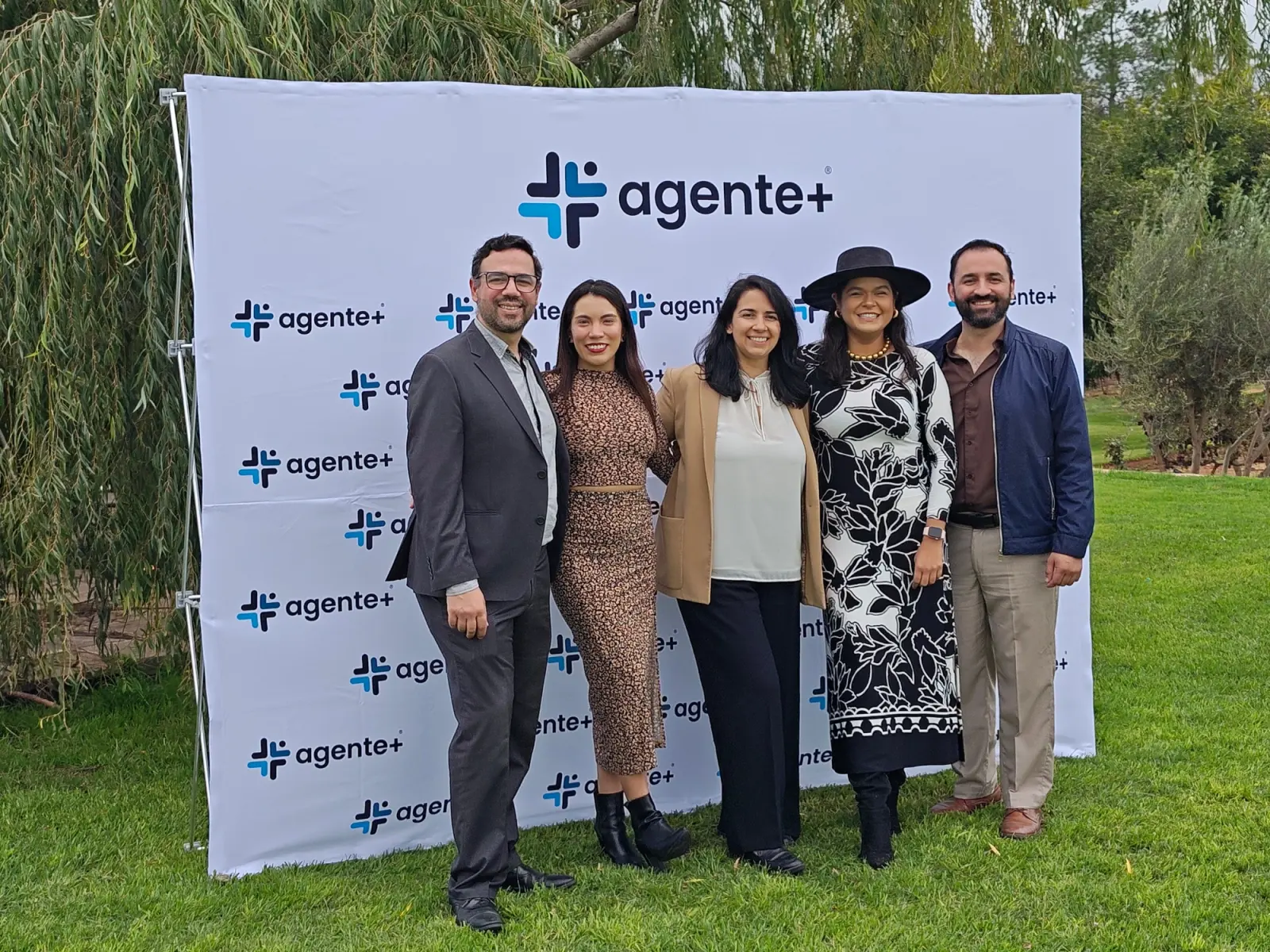 Agentes de Agente Más frente al photocall de la promotoría en un evento