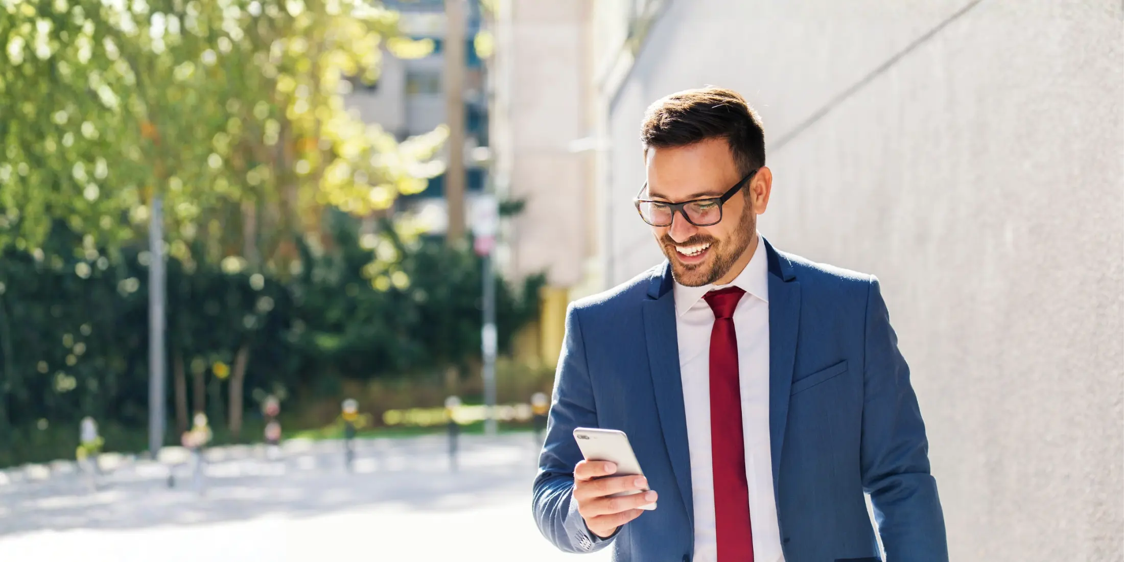 Agente de seguros sonriendo mientras revisa su teléfono en la calle