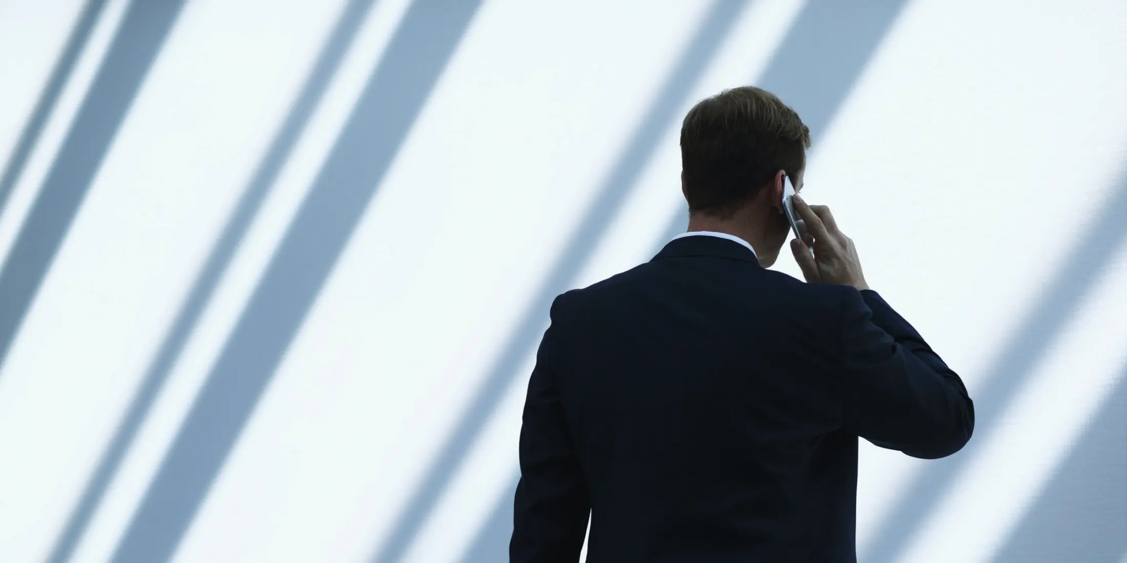 Agente de seguros de espaldas hablando por teléfono junto a un ventanal