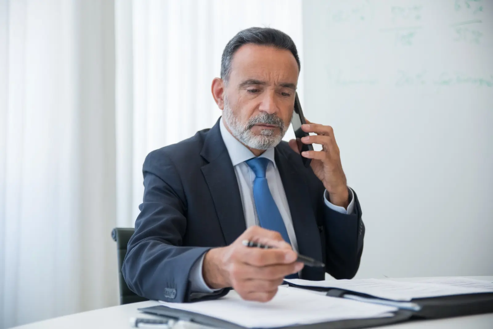 Agente de seguros atendiendo una llamada mientras revisa un expediente