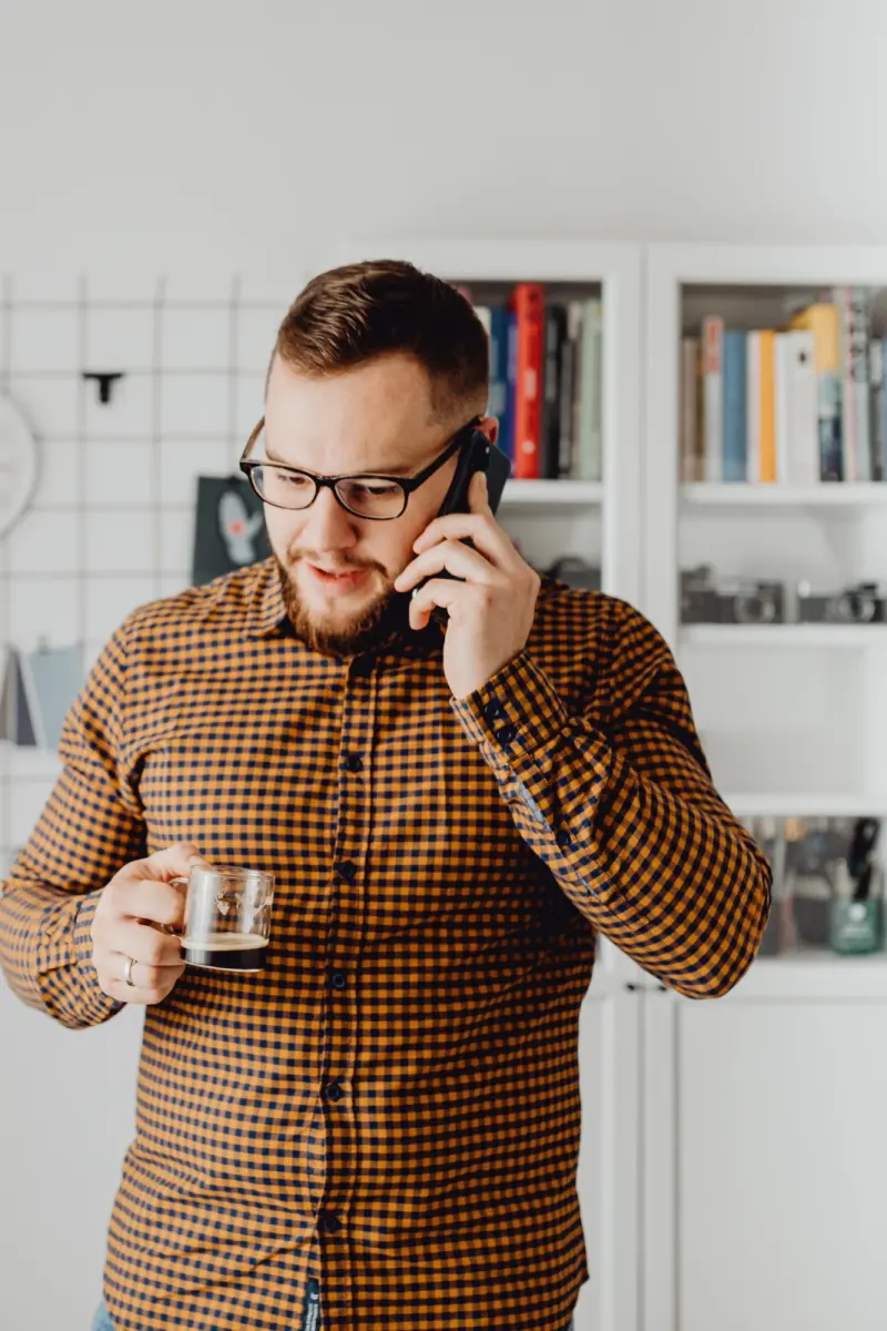 Agente de seguros hablando por teléfono con un café en la mano