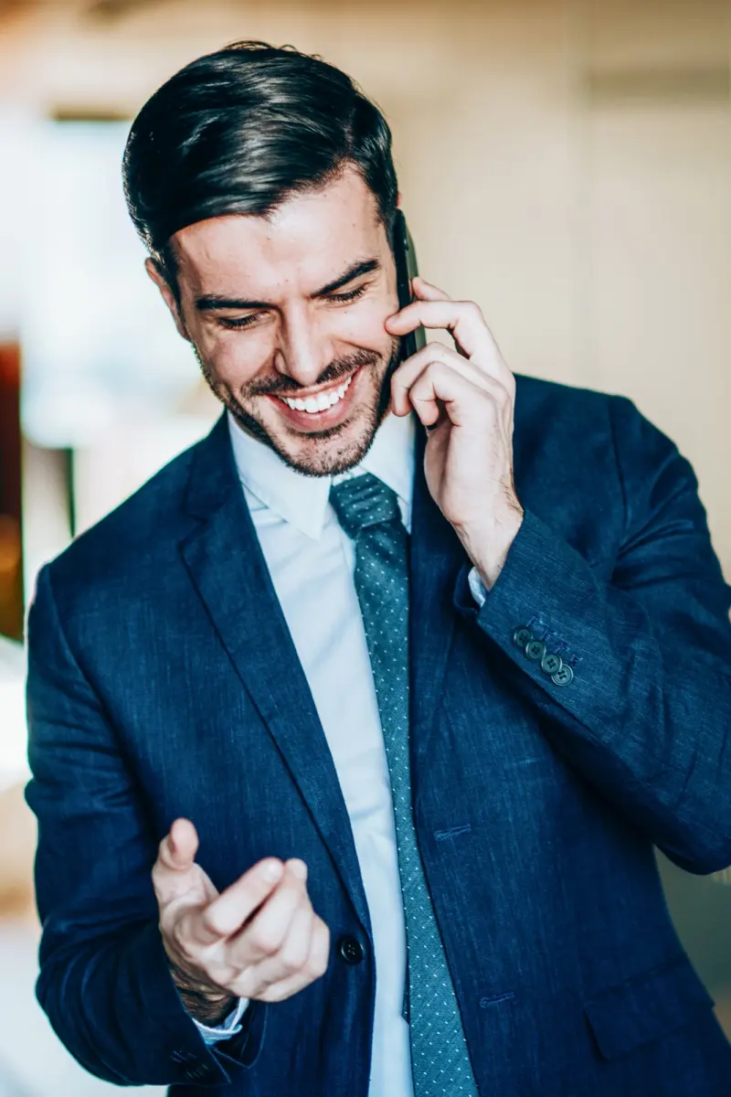 Agente de seguros sonriendo mientras atiende una llamada de pie en la oficina